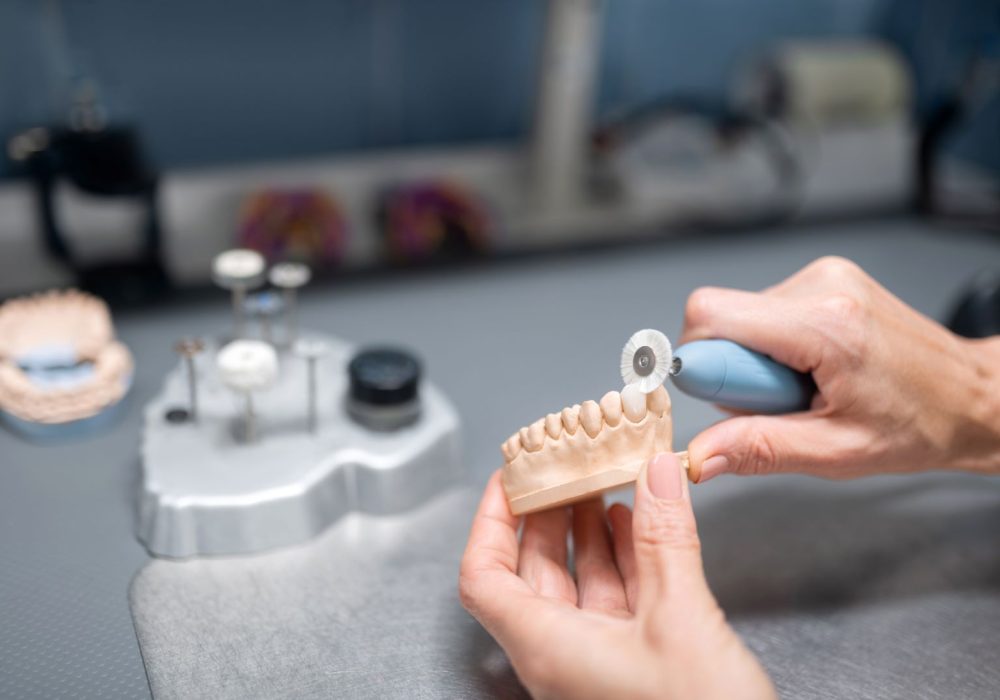 Hands of hard-working dental technician preparing dental prosthesis for the patient